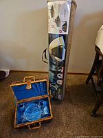 Woods 5-person dome tent in sealed carry bag next to open picnic basket showing dinnerware