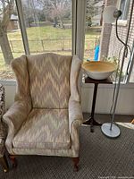 Wingback chair, pedestal table, wooden bowl, portion of lamp