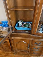 Contents on left lower shelf: tea-for-one set, cup, handled item in blue tray
