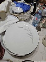 Large dinner plate showing wheat motif and stacked smaller plates in background