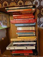 Stack of cookbooks inside cardboard box