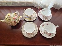 Teapot with lid, four cups with saucers on table