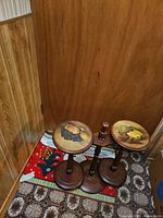 Two wooden pedestal accent tables with fruit motif tops on floor