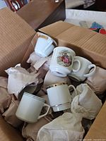 Box containing assorted demitasse cups showing different patterns