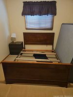 Full view of assembled double wood bed frame showing headboard, footboard, side rails and slats; mattress leaning aside not included