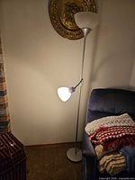 Full view of floor lamp beside chair showing both light fixtures illuminated