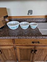 Three Pyrex bowls side by side on countertop showing pattern and sizes