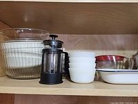 Shelf with enamel dish, glass bowls, French press, milk-glass bowls