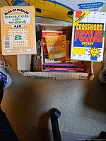 Open box with visible puzzle books including Search a Word Pad, Crossword Puzzles Digest and several smaller booklets