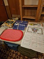 Overall lot showing vinyl tablecloths, boxed napkins, calendar tea towel, red placemats