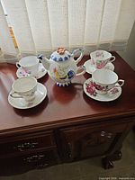 Full lot view showing four teacup-saucer sets and tea-for-one teapot