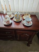 Group view of four teacup sets and floral tea-for-one set