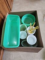 Top view of box showing teal rectangular container, round bowls, cups, spoons