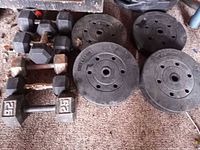 Stacked rubber hex dumbbells and four cast iron plates displayed on floor