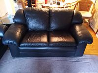 Front view of black leather loveseat showing cushions and armrests