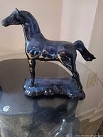 Front left view of blue ceramic horse figurine on glass table