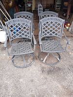 Front view of four gray cast aluminum swivel patio chairs