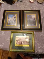 Overview of all three framed prints: two black-framed landscapes, one green-framed cherub