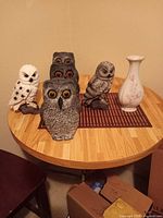 Front view showing five owl figurines and porcelain vase on table
