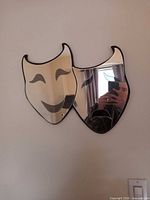 Dual theater mask mirror mounted on wall