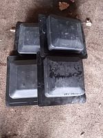 four black plastic pots upside-down showing square bases and surrounding flanges