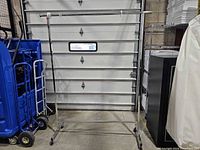 Full view of garment rack, chrome frame, single rail, casters visible