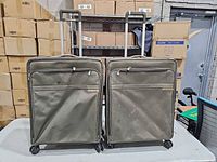 Front view of both olive fabric spinner suitcases with handles extended