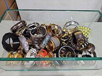 Tray filled with mixed bangles and cuffs showing variety of materials and colours