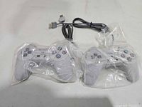 Pair of gray Sony PlayStation wired controllers sealed in plastic