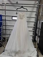 Full front view of Vera Wang ivory wedding dress on hanger showing silhouette and long train