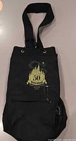 Front view showing gold 50th castle logo, strap, front pocket, side mesh pocket