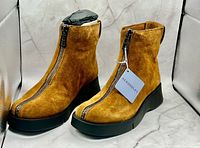 Full view of both tobacco suede boots with tag attached, showing platform soles and front zips