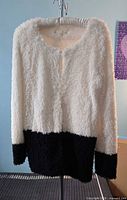 Front view of white and black boucle cardigan on hanger
