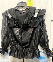 Front view showing metallic floral pattern, ruffle neckline, cold shoulder cutouts, long sleeves, elastic waist and peplum hem