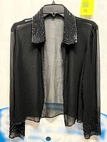 Full front view of black sheer beaded evening jacket on hanger
