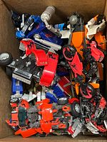 Box with loose red, orange, blue vehicle parts and motorcycles
