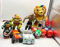 Group shot of all toys including figures, cars, plush lion and playset pieces