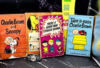 Front view of four Peanuts paperback books and Lucy wristwatch