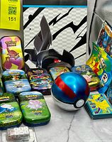 Group shot of tins, Great Ball, binder background, dice and coins