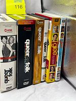 Spines of five DVD box sets: three Queer as Folk Collector’s Edition seasons and two Glee sets