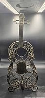 Front view of wrought iron violin wine rack showing scrollwork and bottle openings