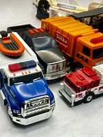 Close-up of several Tonka vehicles including blue Emergency Services Unit truck, black SUV, orange utility truck, red fire engine