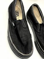 Top view of left and right black Vans slip-on shoes