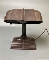 Front view of brown banker-style table lamp showing shade, column and base