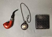 Pipe, pocket watch with chain, cigarette case closed