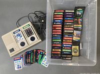 Console, cables, game cartridges in bin, overlays spread out