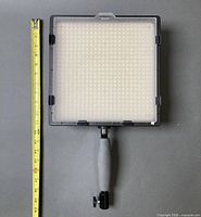 Front of LED panel with attached handle and measuring tape showing 10 x 10 in size