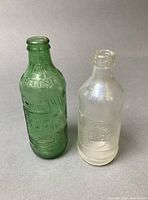Both 7-Up and Pepsi-Cola bottles standing side by side