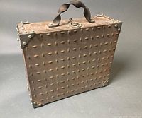 front view of metal briefcase showing riveted exterior, twisted handle and clasp