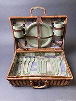 Open picnic basket showing plates, cups and cutlery secured inside